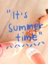 ItÃ¢â¬â¢s Summer time text on blurred image background of woman feet on sand
